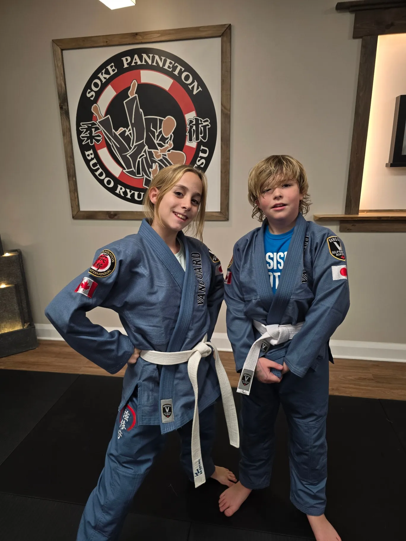 Two teen students in Vanguard uniforms standing together inside the dojo